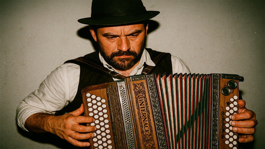 Bärtiger grimmiger Mann mit Hut spielt steirische Harmonika