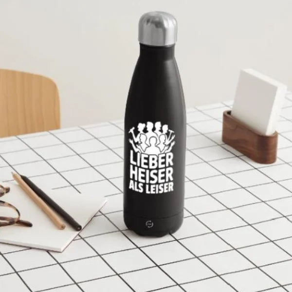 Schwarze Isolierflasche mit dem Chorspruch „Lieber heiser als leiser“ auf einem hellen Schreibtisch.