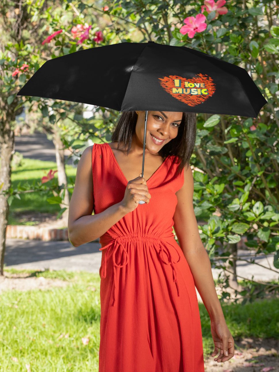 Frau hält schwarzen Regenschirm mit Herzmotiv und dem Text „I love music“ im Garten