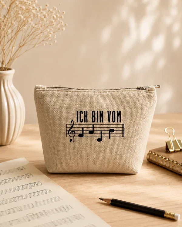 Naturfarbenes Täschchen mit Notenschrift-Motiv „Ich bin vom Fach“ auf einem hellen Tisch mit Notenblättern.
